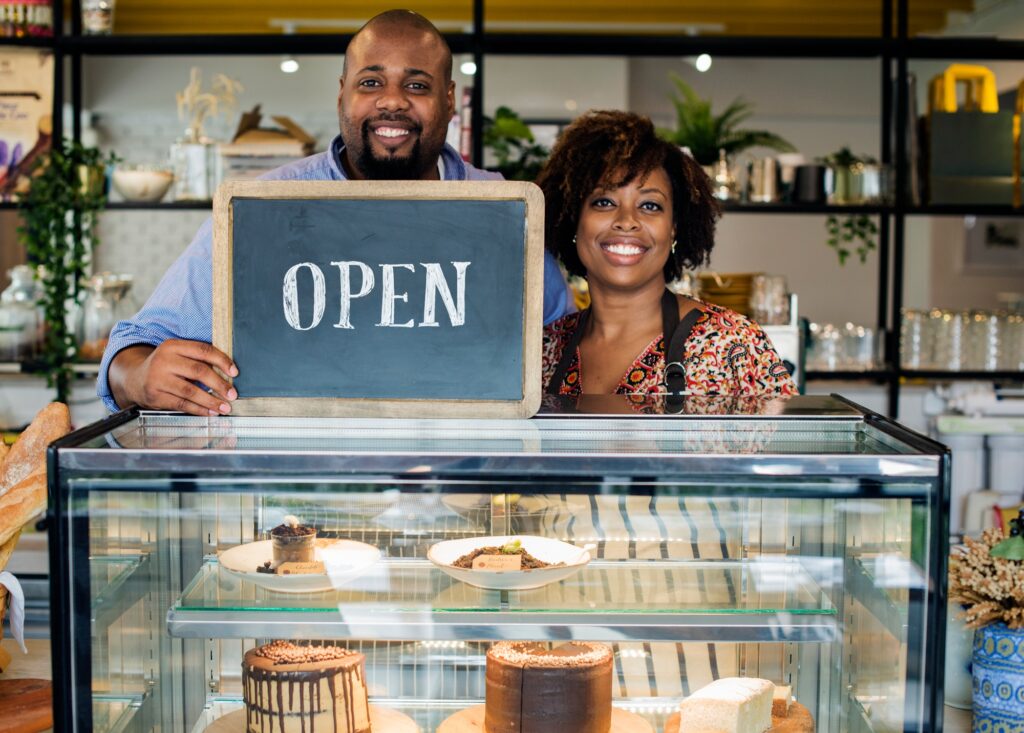 Cake cafe owners with open sign